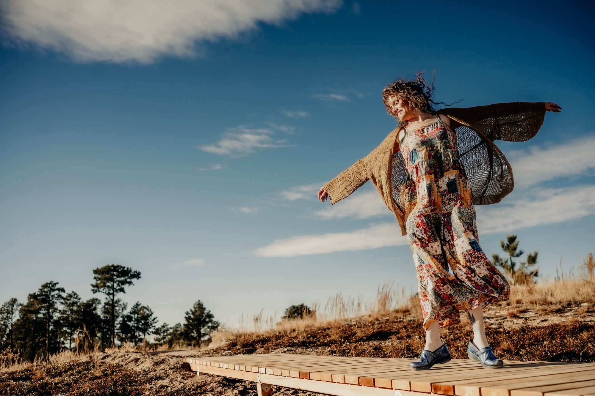 Katharine Zink on a Colorado hillside, arms open, expansive blue sky