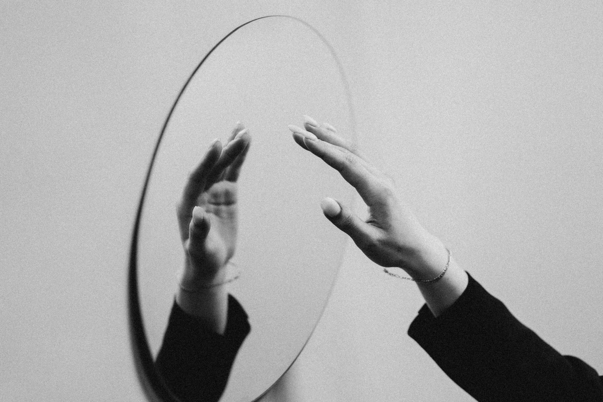 Hand reaching toward a circular mirror